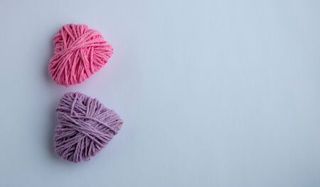 Pink and lilac knitting yarn heart shaped. Valentines day minimal concept. Greeting card with heart on a pink background. Top view. Copy space.の写真素材