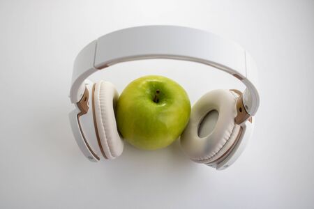 green apple in which headphones are connected. The music player in the shape of an apple with headphones.Fantasy on the theme of music and fruits.の写真素材