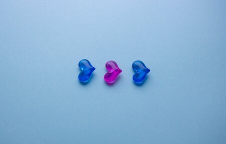 Red and blue glass hearts on the blue background. The symbols of love for Valentines Day