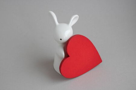 Beautiful ceramic rabbit on white background. statuette of a white rabbit with a red heart.Easter decor.の写真素材