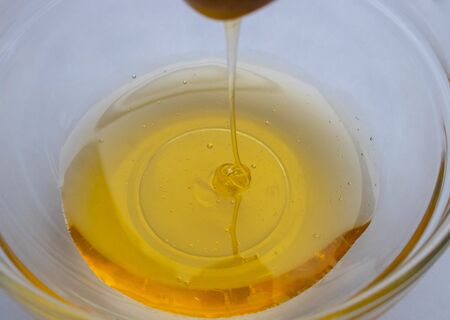 Honey dipper on the bee honeycomb background. Honey tidbit in glass jar and honeycombs wax.の写真素材