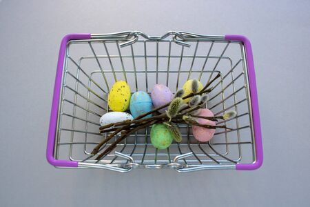 willow twigs and colorful eggs in a grocery basket
