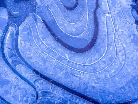 a close-up shot of a blue ice texture on a puddle in frosty winter weather.の写真素材