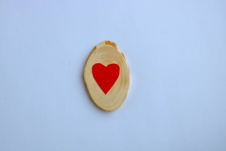 Mother's day, a red heart lies on a tree cut on a white background. Valentine's day, March 8, minimal concept. Greeting card with a heart on a white background. The view from the top.の写真素材