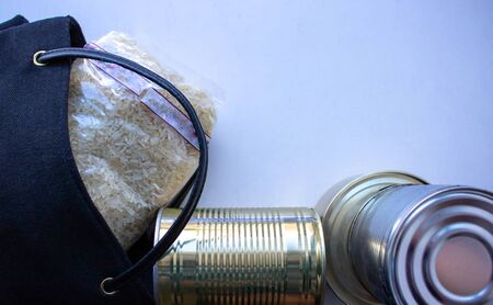 Home delivery of products.Helping people during a pandemic.Rice, tushonka,black bag lie on the gray table.の写真素材