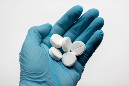 Hand in medical glove with pills on white backgroundの写真素材