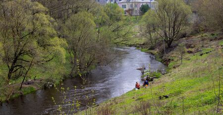 Fishing in the river. Fishermen sit with a fishing rod on the Bank of a small river. - Concept of...