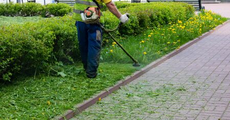 Man mows grass with a gasoline scythe.