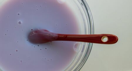 Blueberry yogurt in a glass bowl with a red spoon, isolated on a white background.の写真素材