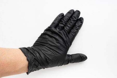 Hand in a black surgical medical glove, isolated on a white background. Production of rubber...