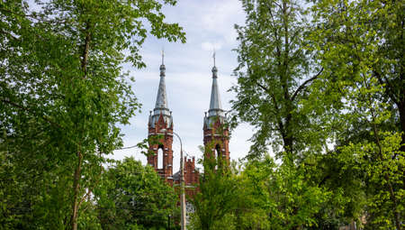 Two spires of the Church in the middle of green foliage against the sky