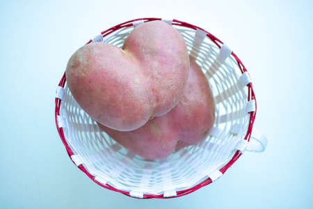 Two heart potatoes in a white basket on a white background.の写真素材