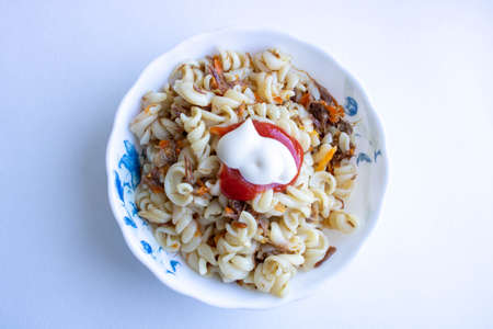 Traditional Soviet Russian dish of pasta, vermicelli, sea paste, with meat on a white plate on a white background. Minimalism is the view from the top.の写真素材