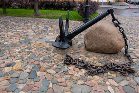 An old black anchor lies on the cobblestones.の写真素材