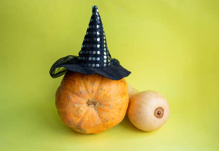The Concept Of Halloween. An orange pumpkin in a witch's hat and a long yellow pumpkin on a yellow background.の写真素材