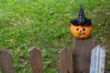 A cheerful pumpkin in a Witch's hat is sitting on the fence.The Concept Of Halloween.の写真素材