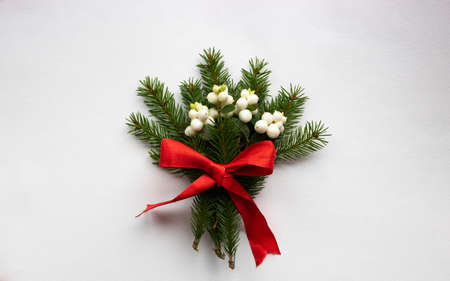 Christmas bouquet with fir branches, red bow and white dogwood berries on a white background. Christmas card. The theme of a winter holiday. Happy New Year.の写真素材