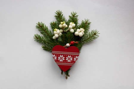 Christmas bouquet with fir branches, red wooden heart and white dogwood berries on a white...