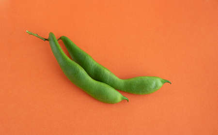 Soy beans close-up, green soy pod on orange background.
