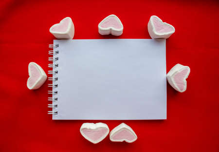 Hearts - marshmallow candies and Notepad, isolated on a red background.の写真素材