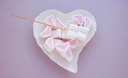 Heart-shaped marshmallow on a white plate on a pink background. The concept of mother's Day, Valentine's Day.の写真素材