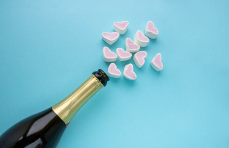 An open bottle of champagne and hearts on a blue background. Holiday concept, New year, Valentine's Day, March 8の写真素材