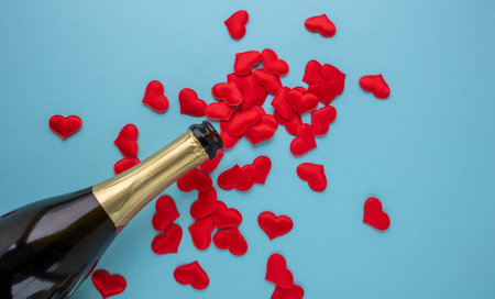 An open bottle of champagne and red hearts on a blue background. Holiday concept, New Year, Valentine's Day, March 8.の写真素材
