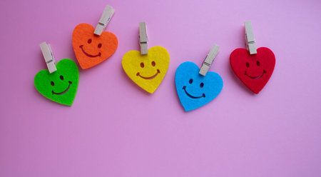 Bright hearts with smiles and small clothespins on a pink background. At the bottom is a place for...