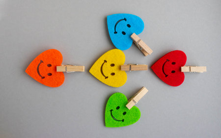 Bright hearts with smiles and small clothespins on a gray background.