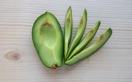 Slices of ripe avocado lie on a light cutting board.