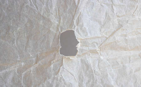 Abstract background of beige crumpled paper with a hole.の写真素材