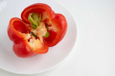 Red sliced pepper on a white plate, isolated on a white background. Space for your text.の写真素材