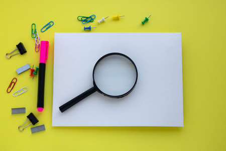 On a yellow background, stationery items, a magnifying glass, an envelope. The concept of school, office, travel.の写真素材