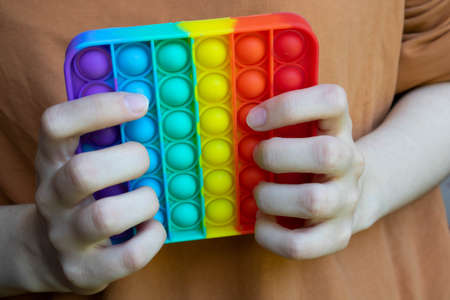 Hands hold a touch-sensitive fidget toy. Blue and Orange Funny Interactive Anti-stress Silicone Toys.の写真素材