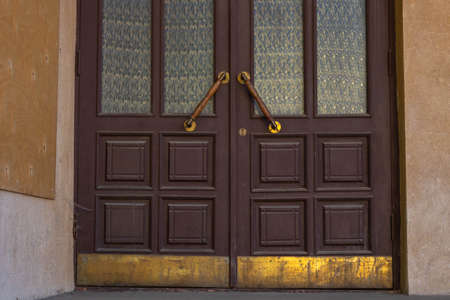 Antique door handles on a brown wooden door with fluted panes