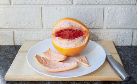 Fresh healthy grapefruit on a white plate on the kitchen table. Creative concept of minimal food....