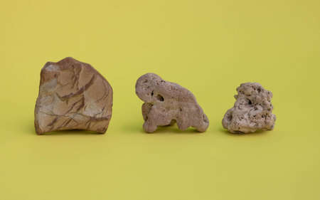 A collection of stones. Various types of pebbles are stones with a soft shadow on a yellow...