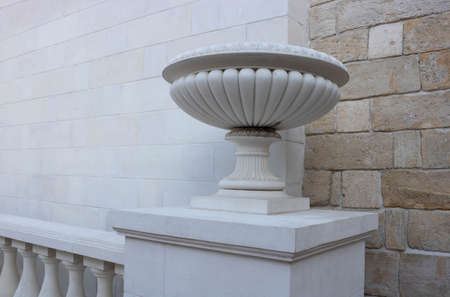 Plaster vase on a pedestal on a decorative background. Decorative element of architecture, close-up.の写真素材