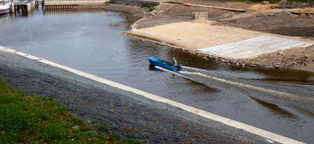 A fisherman in a blue motor boat floats to the pierの写真素材