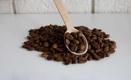 Aromatic coffee beans in a wooden spoon, coffee beans for the production of delicious coffee. whole coffee beans for grinding.の写真素材