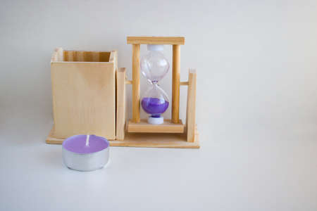 On a white background, a transparent hourglass with flowing lilac sand. The old classic timer. The...