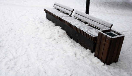 Wooden bench in the Park, covered with snow. Beginning of winter.