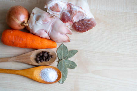 Raw pork meat and leg, carrots and onions, salt and pepper on the kitchen table for making jelly.の写真素材