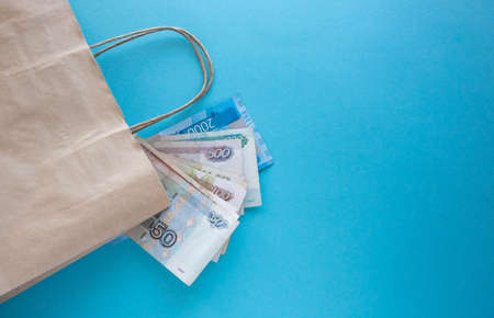 A bundle of Russian money and a paper bag on a blue background. Place for your textの写真素材