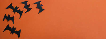 Black paper bats fly on an orange background. A banner for Halloween.Halloween Conceptの写真素材