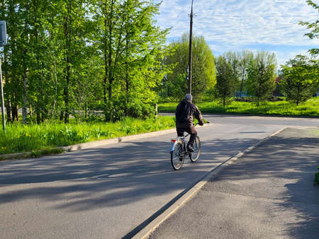 An elderly male cyclist rides a bicycle in a public park, his face is not visible.の写真素材