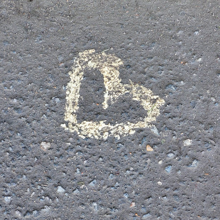 A heart made with white paint on gray asphalt.A symbol of love.Copy spaceの写真素材