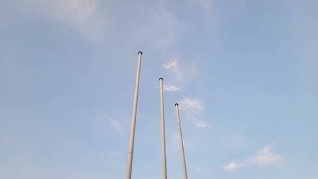 Three flagpoles against a blue sunset skyの写真素材