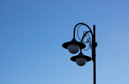 An iron lantern against the blue sky. Road lighting, light bulbs in a lamppost