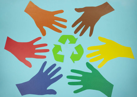 The international recycling sign is a Mobius loop and multicolored hands cut out of paper on a blue background. November 15 - Waste Recycling Day.の写真素材
